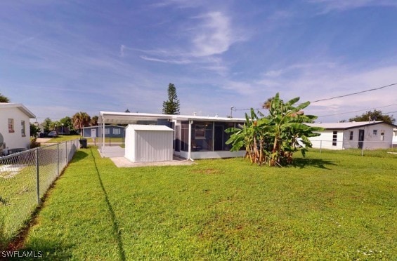 rear view of house with a yard, a fenced backyard, and a sunroom