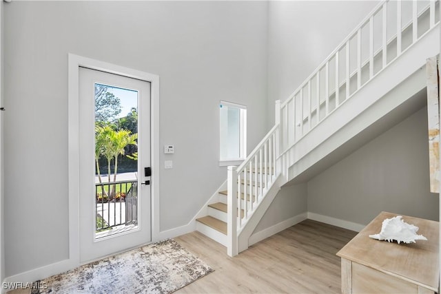 entrance foyer featuring stairs, baseboards, and wood finished floors