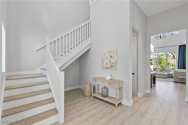 stairs featuring a high ceiling, baseboards, and wood finished floors