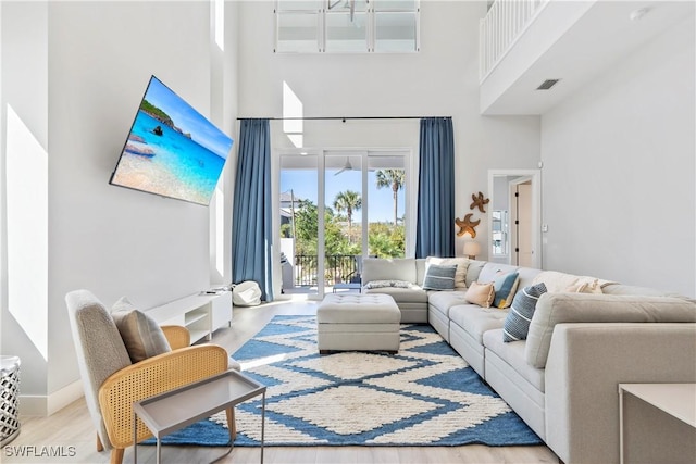 living area featuring baseboards, visible vents, a high ceiling, and wood finished floors