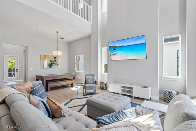 living area with a high ceiling, wood finished floors, a wealth of natural light, and baseboards