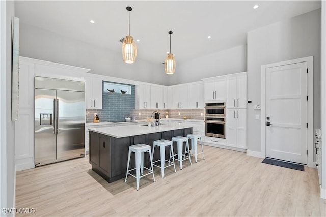 kitchen featuring appliances with stainless steel finishes, backsplash, a breakfast bar, and white cabinets