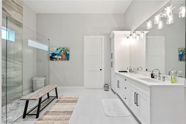 bathroom with double vanity, a stall shower, a sink, and baseboards