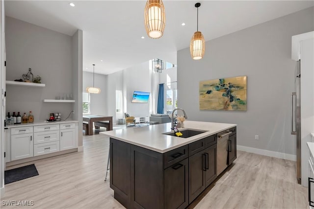 kitchen with light wood-type flooring, light countertops, a sink, and stainless steel dishwasher