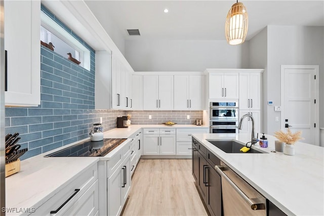 kitchen with light countertops, visible vents, decorative backsplash, appliances with stainless steel finishes, and a sink