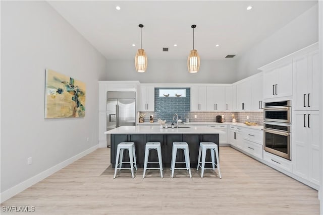 kitchen featuring a center island with sink, a breakfast bar area, tasteful backsplash, appliances with stainless steel finishes, and a sink