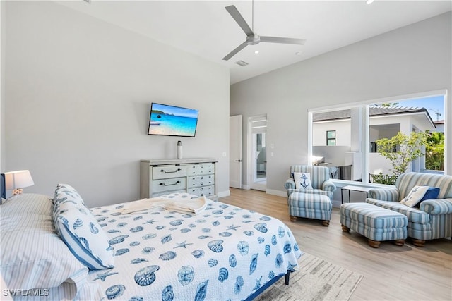 bedroom with a ceiling fan, baseboards, light wood-style flooring, and a towering ceiling