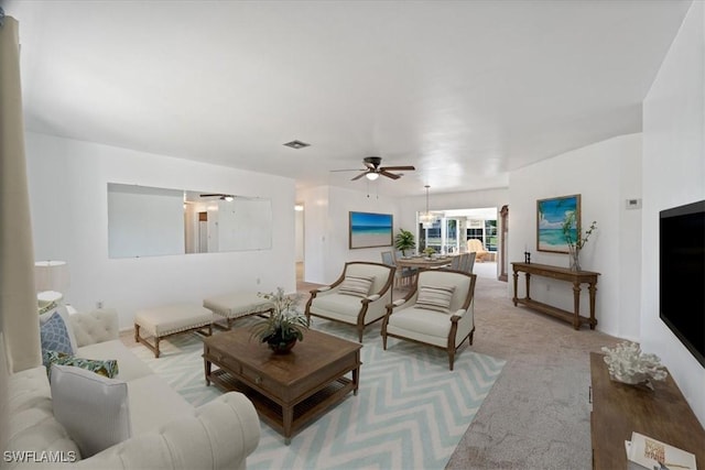 living area featuring a ceiling fan, visible vents, and light carpet