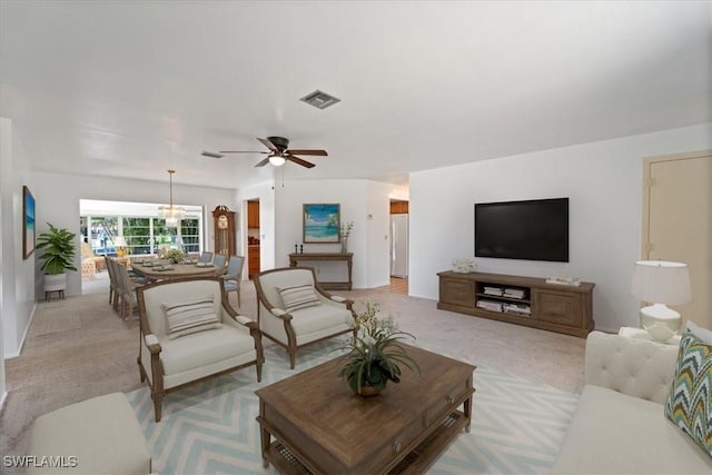 living area with ceiling fan with notable chandelier, visible vents, and light carpet