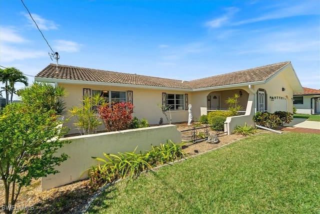 exterior space with stucco siding, a garage, a yard, and a tile roof