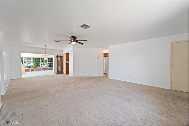 unfurnished living room with ceiling fan with notable chandelier, visible vents, and light carpet