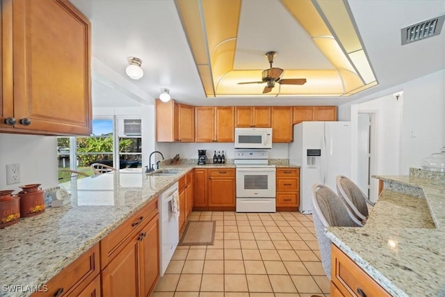 kitchen featuring white appliances, light stone counters, a ceiling fan, visible vents, and a raised ceiling