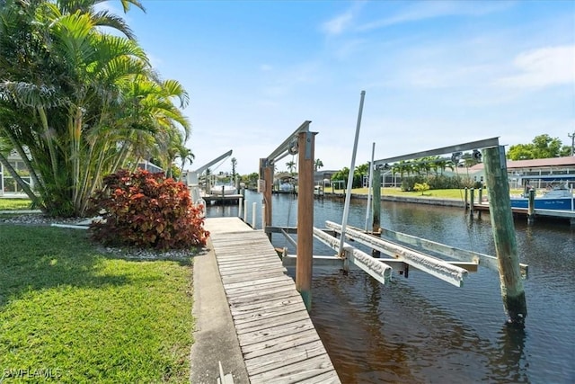 view of dock featuring a lawn, a water view, and boat lift