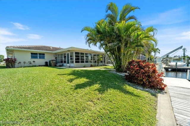 back of property featuring a lawn, a sunroom, and stucco siding