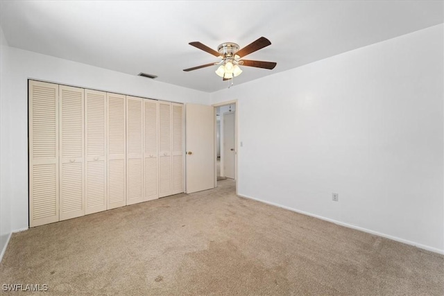 unfurnished bedroom with a closet, visible vents, ceiling fan, and carpet