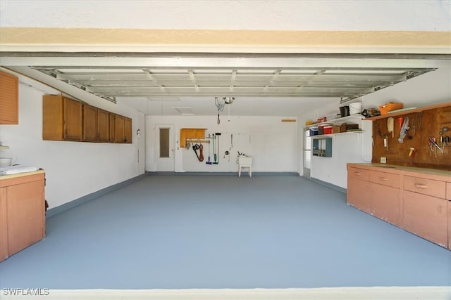 garage featuring a workshop area, baseboards, and a sink