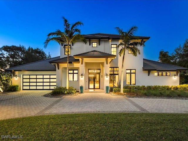 view of front of home with decorative driveway, french doors, a garage, and stucco siding