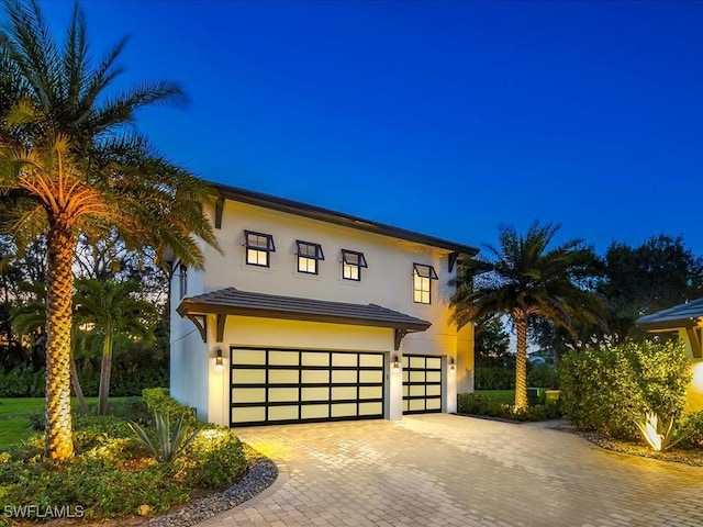 contemporary house with decorative driveway, an attached garage, and stucco siding