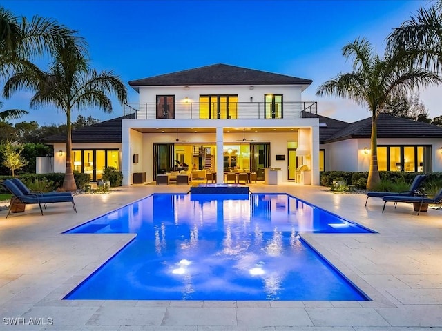 pool at dusk with a ceiling fan, an outdoor pool, outdoor lounge area, a jacuzzi, and a patio area