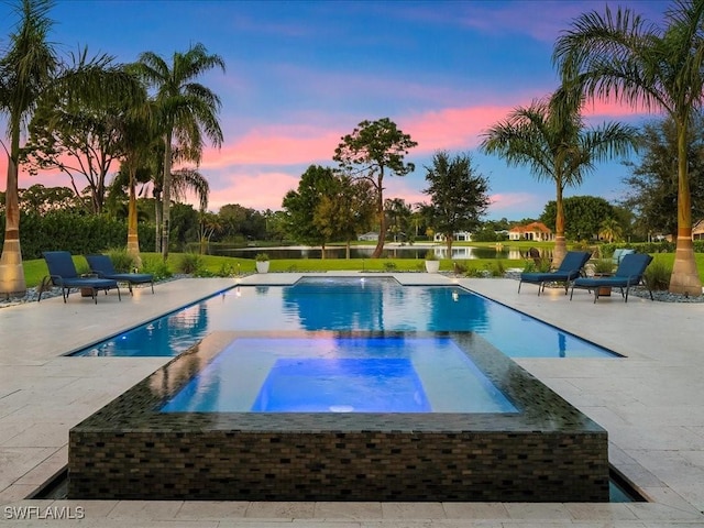 pool at dusk with a patio area, an outdoor pool, and an in ground hot tub