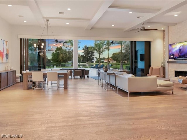 living area featuring visible vents, beamed ceiling, wood finished floors, recessed lighting, and a lit fireplace