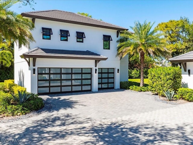 view of front facade with stucco siding, decorative driveway, and a garage