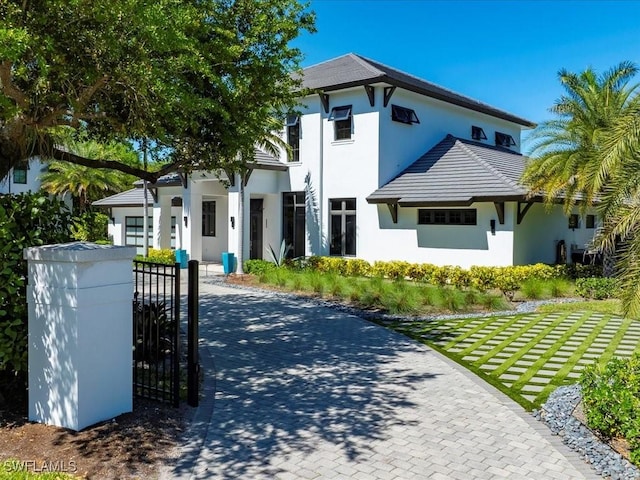 view of front facade with stucco siding, driveway, and a gate