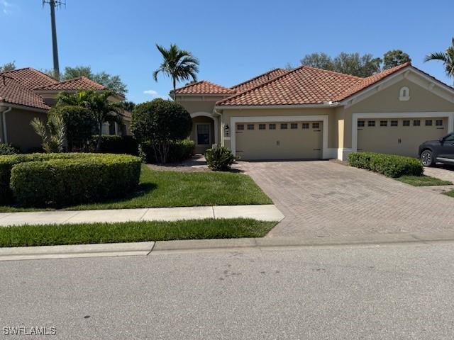 view of front of property with a garage, stucco siding, driveway, and a tile roof