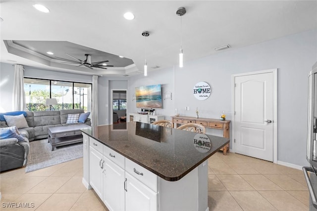 kitchen with open floor plan, a tray ceiling, light tile patterned floors, white cabinetry, and a ceiling fan