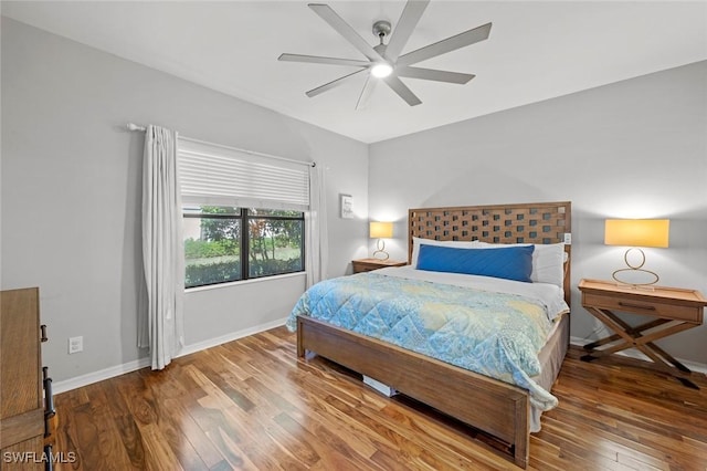 bedroom with hardwood / wood-style floors, a ceiling fan, and baseboards