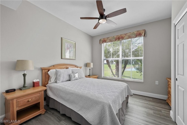 bedroom with ceiling fan, wood finished floors, and baseboards