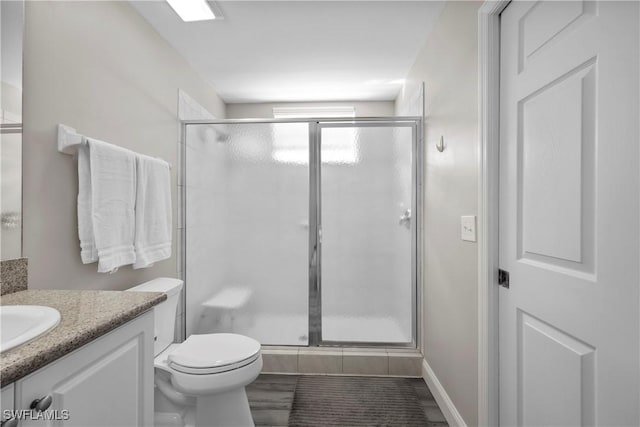 bathroom featuring toilet, a stall shower, and vanity