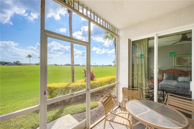 sunroom / solarium featuring plenty of natural light, a ceiling fan, and a rural view