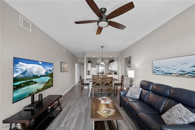 living room featuring baseboards, visible vents, a ceiling fan, lofted ceiling, and light wood-style flooring