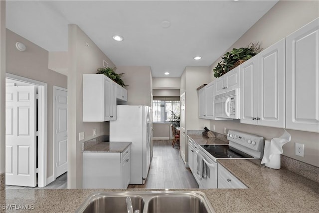 kitchen featuring light wood finished floors, recessed lighting, white cabinetry, a sink, and white appliances