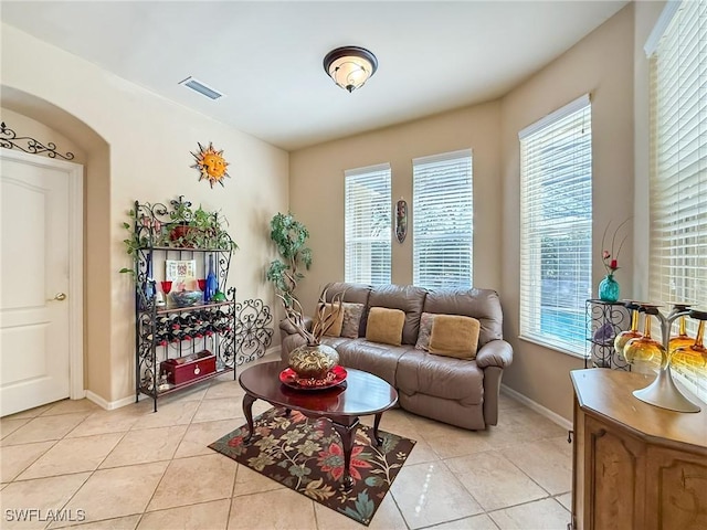 living room with light tile patterned floors, visible vents, and baseboards