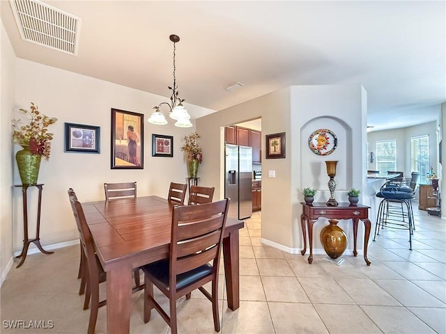 dining area featuring light tile patterned floors, visible vents, baseboards, and a chandelier