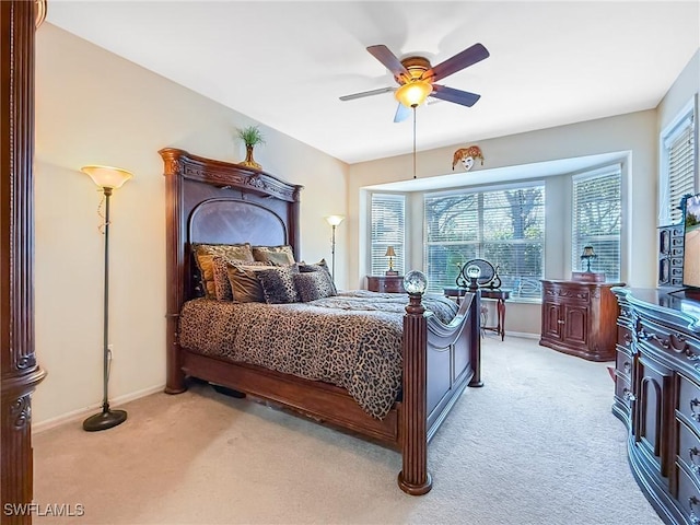 bedroom featuring light colored carpet, a ceiling fan, and baseboards