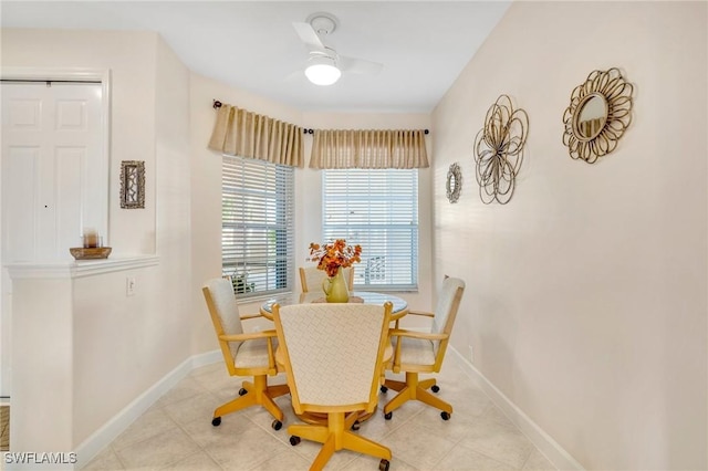 tiled dining space featuring ceiling fan and baseboards