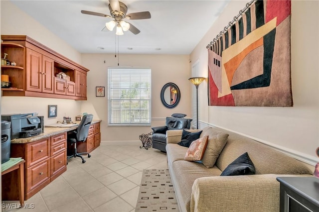 office featuring light tile patterned flooring, built in desk, baseboards, and a ceiling fan