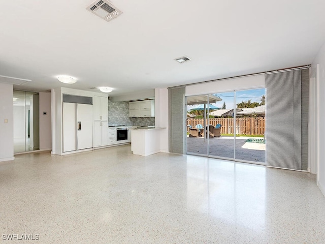 unfurnished living room with visible vents and light speckled floor