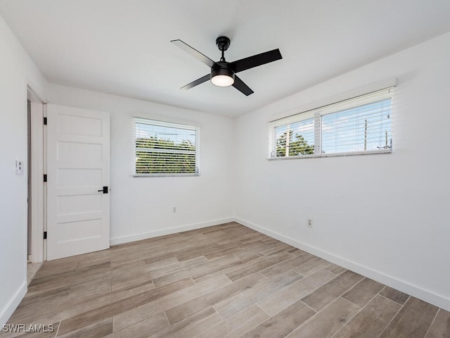 empty room featuring light wood-style flooring, a healthy amount of sunlight, ceiling fan, and baseboards