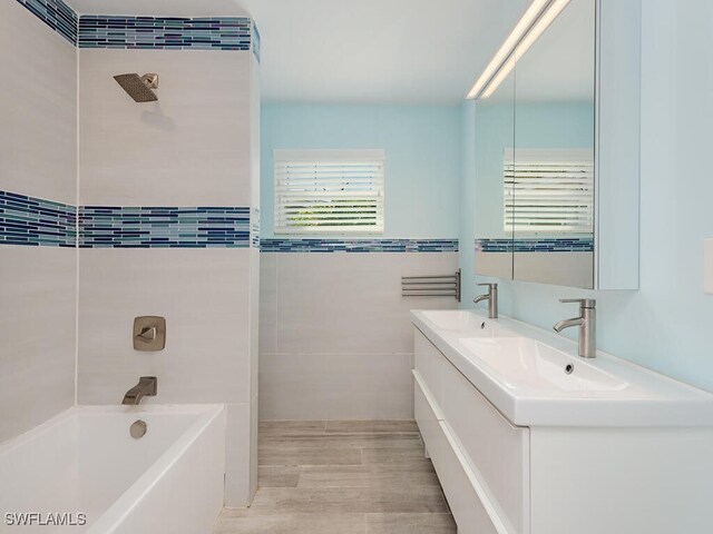 full bathroom with double vanity, tile walls, and a sink