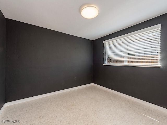 unfurnished room with speckled floor and baseboards