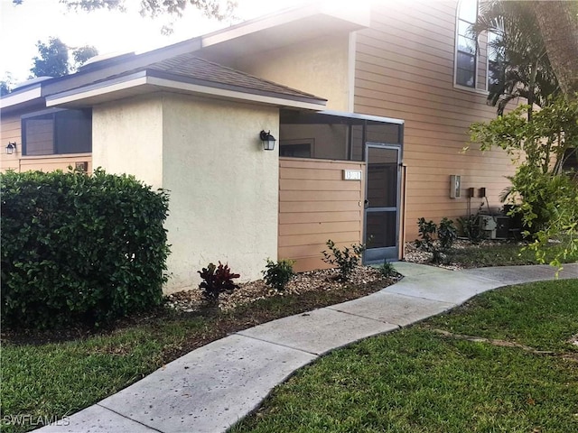 exterior space with stucco siding and roof with shingles