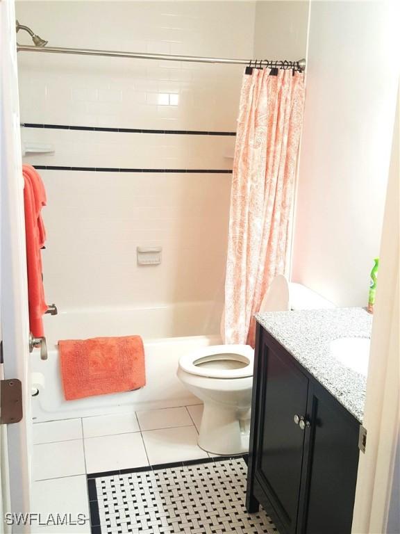 bathroom featuring tile patterned floors, toilet, shower / bath combo with shower curtain, and vanity