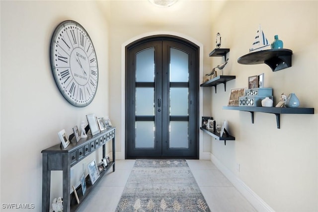 entryway with arched walkways, tile patterned flooring, french doors, and baseboards