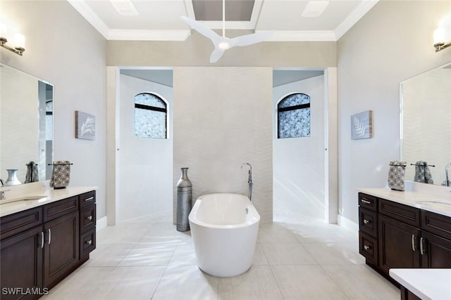 full bath with crown molding, a soaking tub, and two vanities