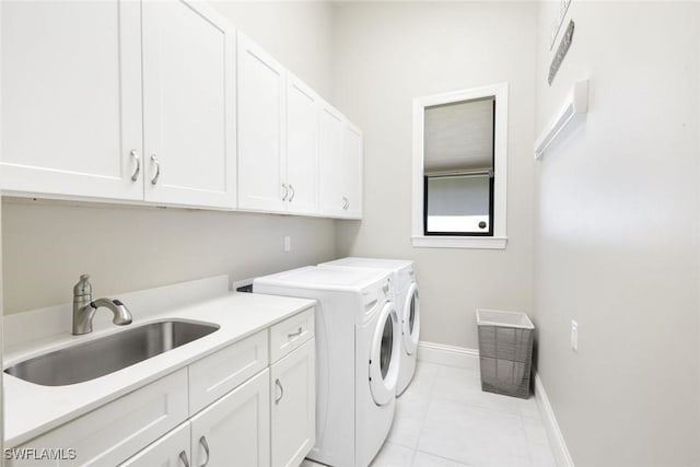 laundry room with a sink, washing machine and dryer, cabinet space, light tile patterned floors, and baseboards