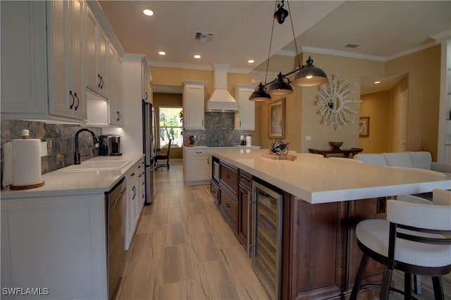 kitchen featuring visible vents, beverage cooler, a breakfast bar, custom range hood, and appliances with stainless steel finishes